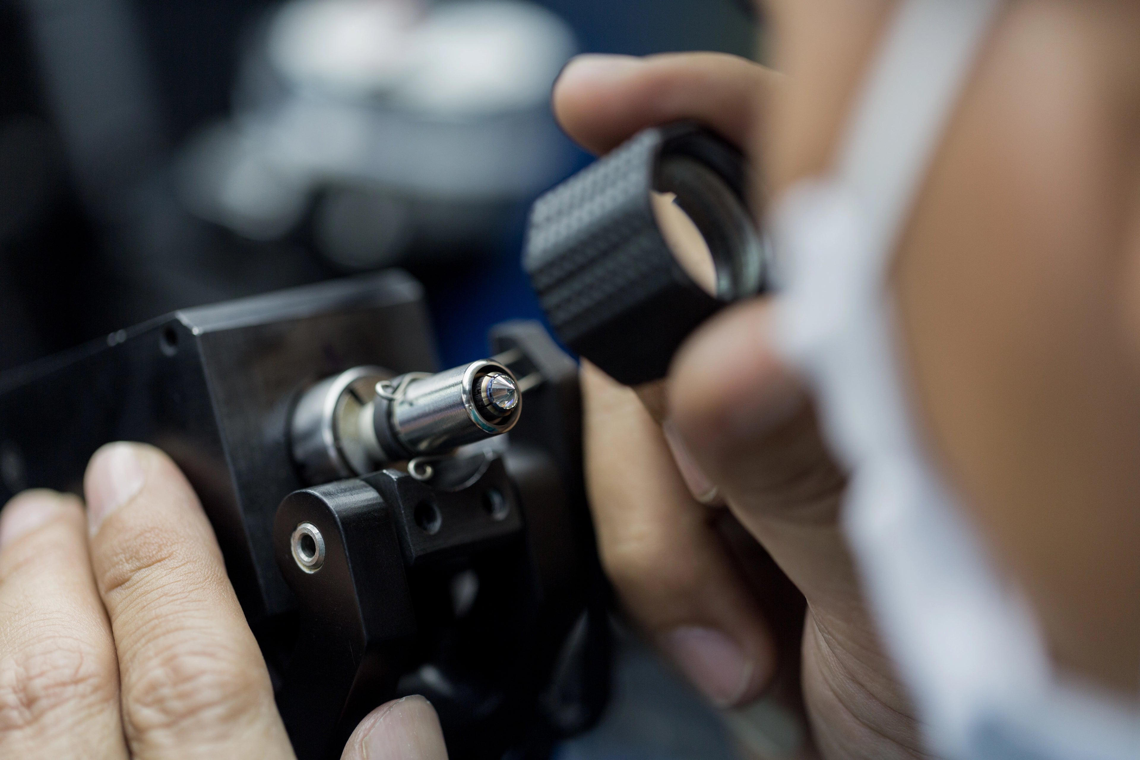 Jeweler inspecting a diamond with precision equipment, representing J'ENCHANTE's careful diamond selection and craftsmanship standards.