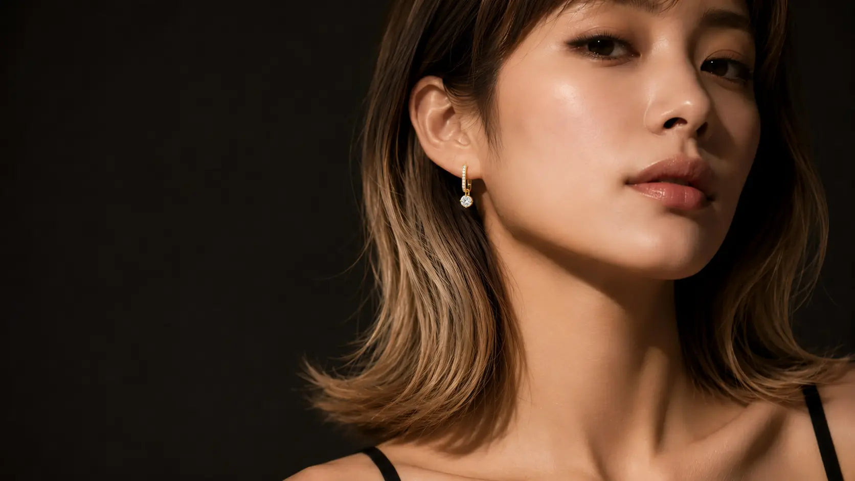Model wearing the J'ENCHANTE 520MOD 18K gold star diamond drop earring in warm studio lighting.