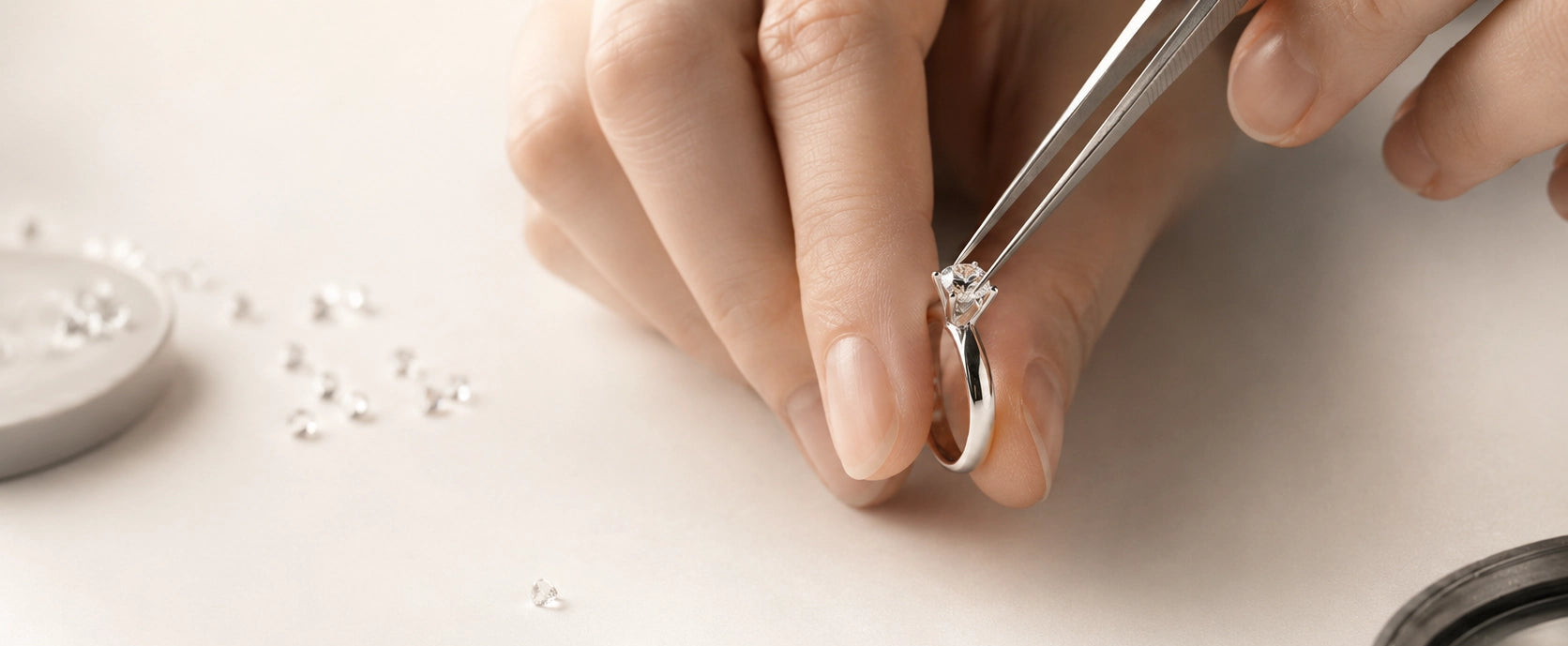 Close-up of a diamond ring being inspected with tweezers during the J'ENCHANTE bespoke jewelry process.