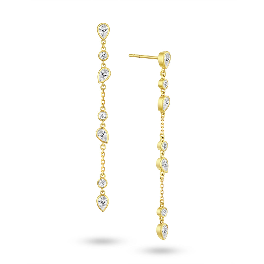 Angled view of the J'ENCHANTE DEW cascading teardrop and round diamond earrings. The image highlights the delicate gold setting and the exquisite layered cascade of 7 alternating diamond cuts. Catching light with every subtle movement, this expressive design adds depth and sophisticated brilliance without overwhelming.
