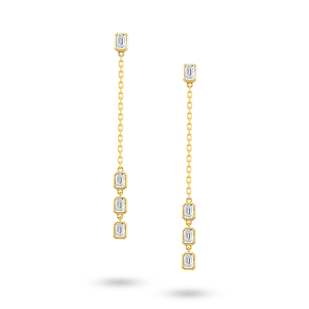 Front view of the J'ENCHANTE DEW geometric drop diamond earrings in gold. Featuring a clean, architectural 50mm drop, each earring presents a vertical sequence of 4 emerald-cut diamonds (approx. 0.7 carats) aligned on a delicate chain, evoking droplets tracing a structured path with cool, controlled brilliance.