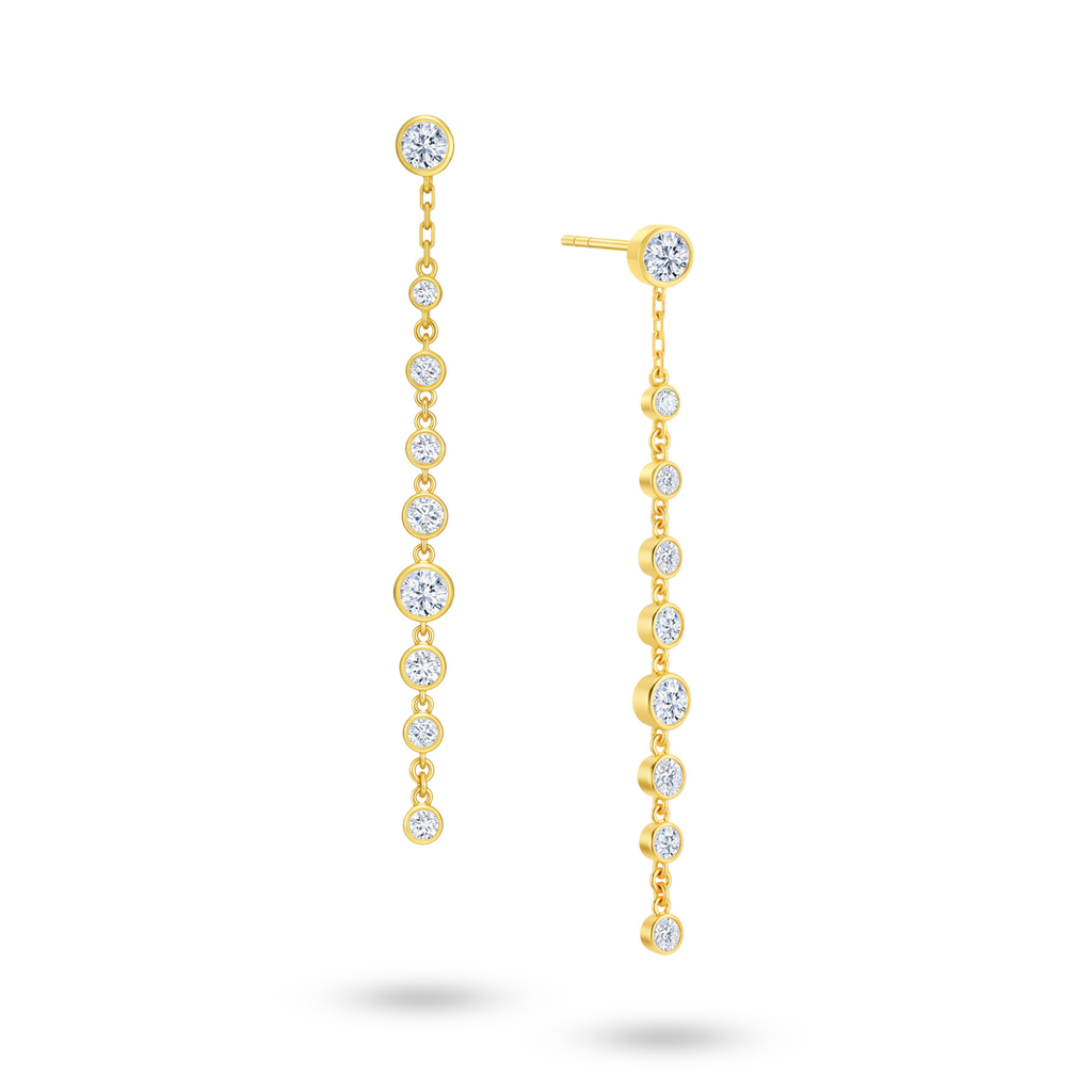 Angled view of the J'ENCHANTE DEW linear droplet diamond earrings. The image highlights the delicate gold setting and the precise vertical alignment of the round diamonds. Balanced between precision and movement, this design introduces a composed rhythm of light that perfectly complements confident workwear or formal looks.