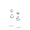 Front view of the J'ENCHANTE The Dualis drop earrings in 18K white gold. Defined by a pure expression of duality, each earring pairs a precise round brilliant diamond with a gracefully suspended pear-shaped drop (4 diamonds totaling approx. 6.1 carats). The minimal connection enhances a sense of lightness, capturing the perfect balance between strength and softness in its purest form.