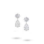 Front view of the J'ENCHANTE The Dualis drop earrings in 18K white gold. Defined by a pure expression of duality, each earring pairs a precise round brilliant diamond with a gracefully suspended pear-shaped drop (4 diamonds totaling approx. 6.1 carats). The minimal connection enhances a sense of lightness, capturing the perfect balance between strength and softness in its purest form.