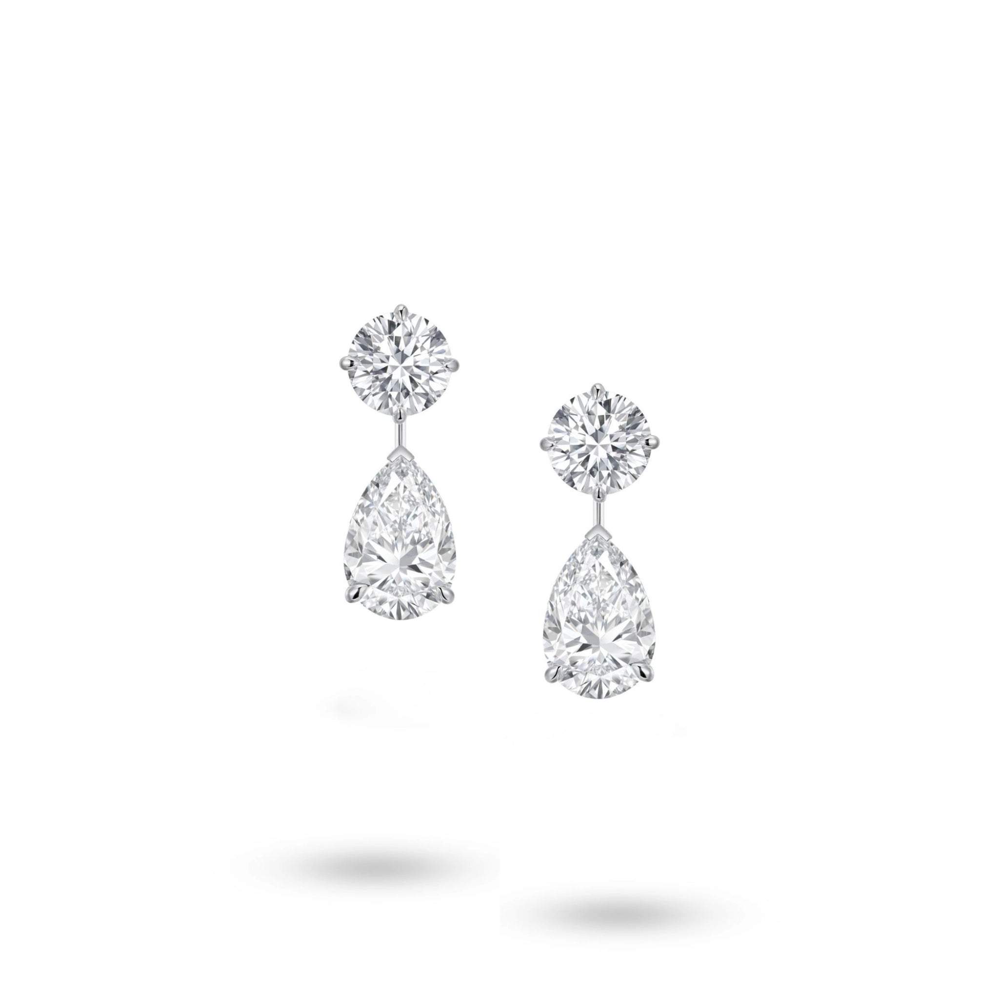 Front view of the J'ENCHANTE The Dualis drop earrings in 18K white gold. Defined by a pure expression of duality, each earring pairs a precise round brilliant diamond with a gracefully suspended pear-shaped drop (4 diamonds totaling approx. 6.1 carats). The minimal connection enhances a sense of lightness, capturing the perfect balance between strength and softness in its purest form.