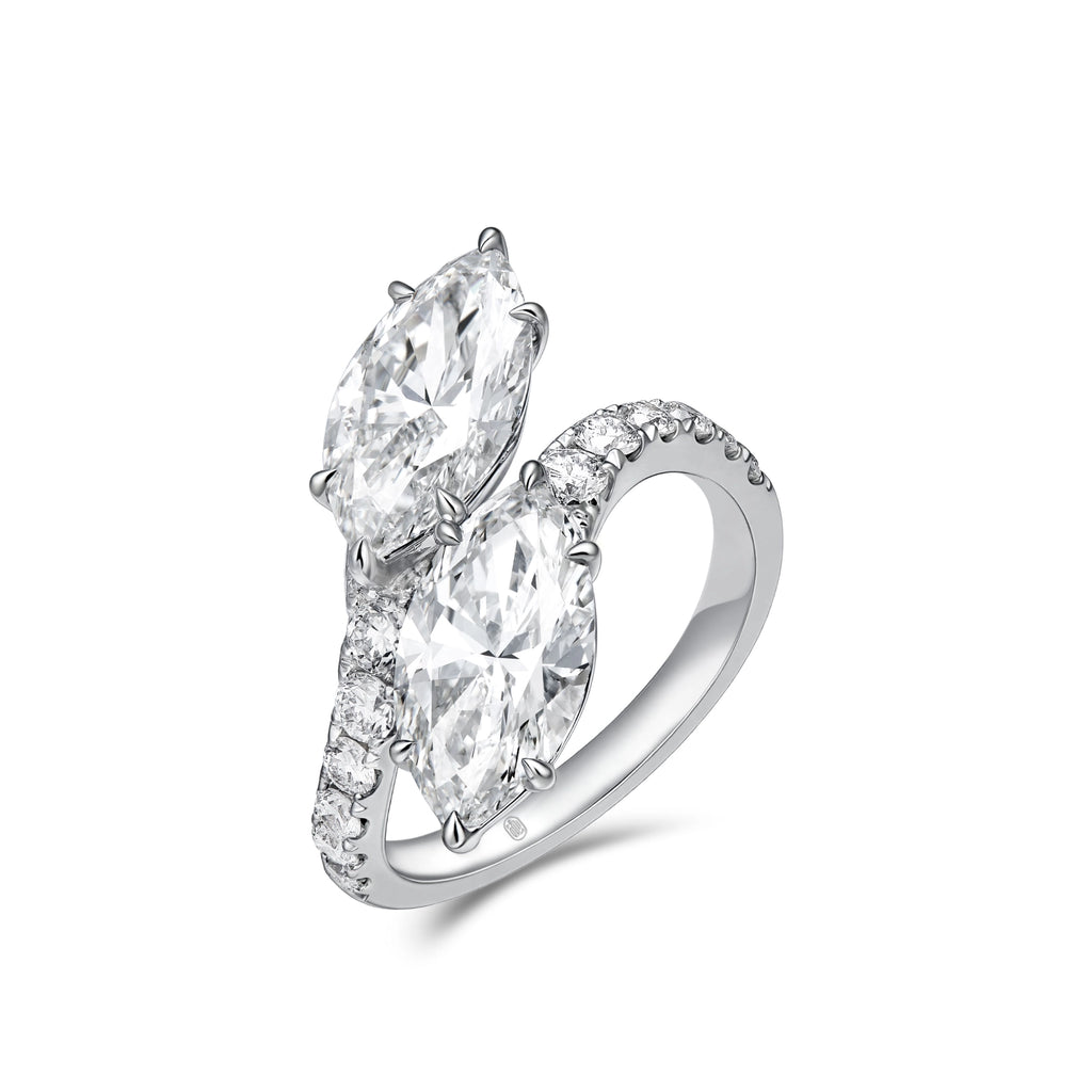 Angled view of the J'ENCHANTE DUO marquise diamond bypass ring. The perspective highlights the sculptural 18K white gold setting and the flowing lines of the pavé-set band. The elevated 2-carat marquise diamonds catch the light brilliantly, emphasizing the ring's striking depth and dynamic movement.