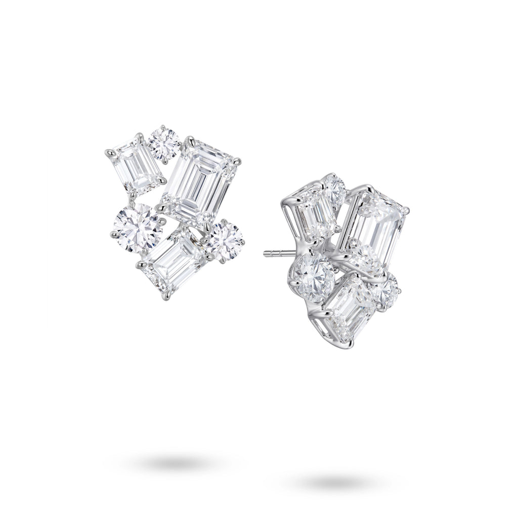Angled view of the J'ENCHANTE The Facette Structure statement diamond earrings. The perspective reveals the sculptural 18K white gold setting and secure earring posts. The offset formation of emerald-cut and round diamonds builds striking three-dimensional depth, softening sharp modern geometry with a luminous, architectural rhythm.