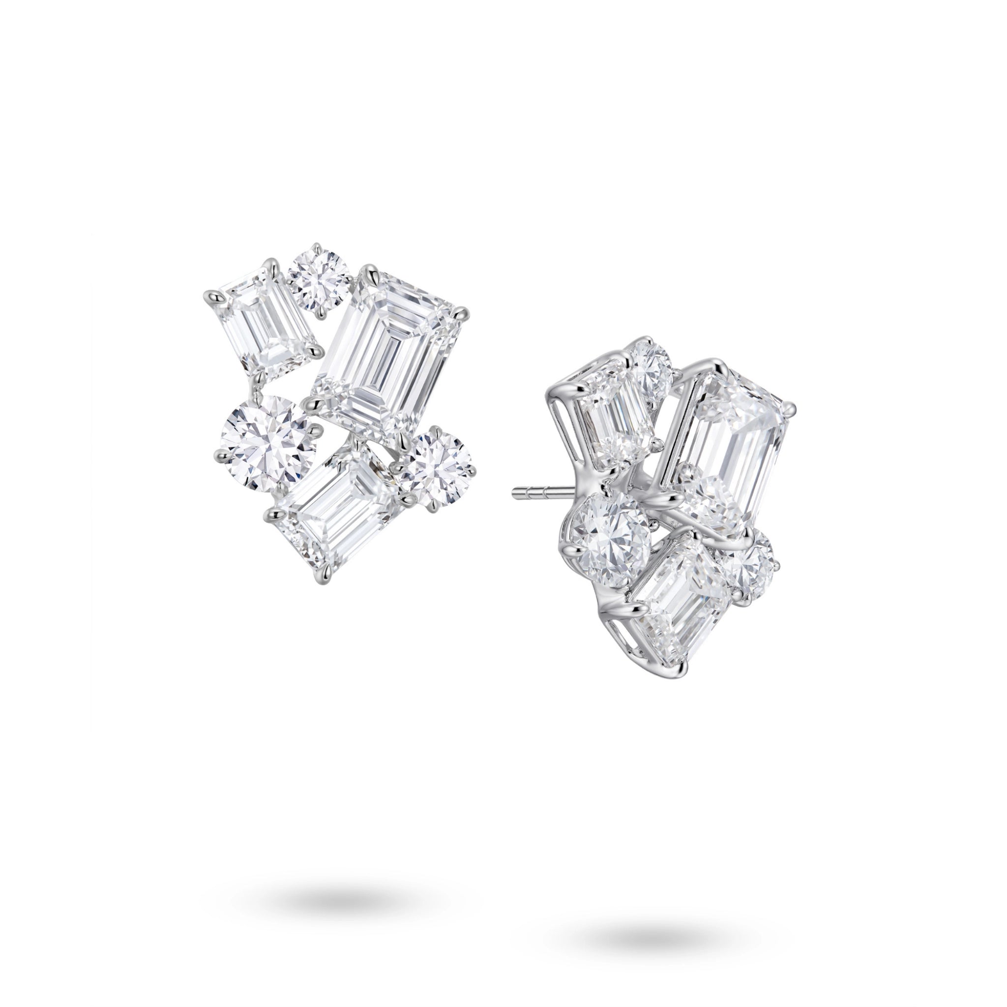 Angled view of the J'ENCHANTE The Facette Structure statement diamond earrings. The perspective reveals the sculptural 18K white gold setting and secure earring posts. The offset formation of emerald-cut and round diamonds builds striking three-dimensional depth, softening sharp modern geometry with a luminous, architectural rhythm.