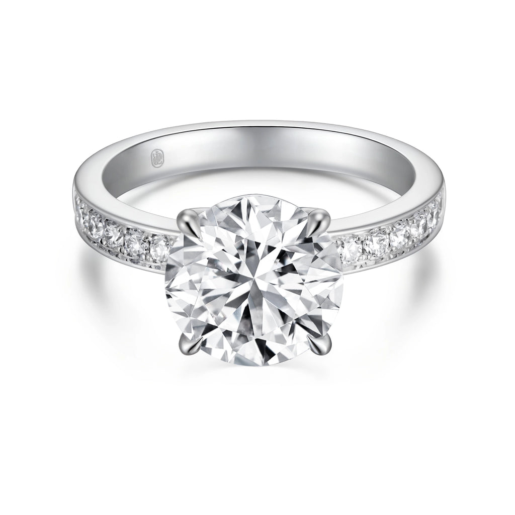 Front view of the J'ENCHANTE JOY 2-carat pavé band diamond ring in 18k white gold, featuring a classic four-prong setting and a center stone enhanced by a delicate pavé-set band with 12 round diamonds.