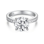 Front view of the J'ENCHANTE JOY 2-carat pavé band diamond ring in 18k white gold, featuring a classic four-prong setting and a center stone enhanced by a delicate pavé-set band with 12 round diamonds.
