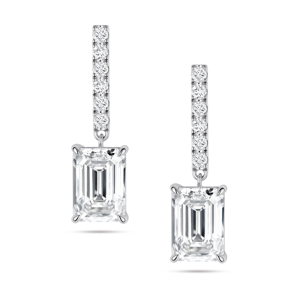 Front view of the J'ENCHANTE JOY emerald bar stud earrings, featuring slim vertical bars pavé-set with 12 diamonds (approx. 0.2 carats). The clean lines of the pavé bar create a refined, architectural contrast with the distinct step-cut brilliance of the suspended emerald-cut focal stones.