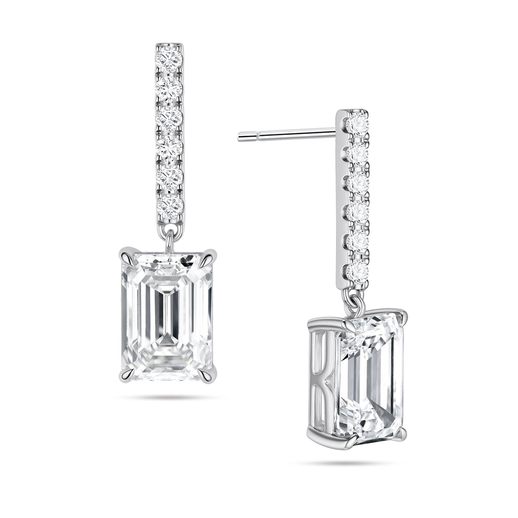 Angled view of the J'ENCHANTE JOY emerald bar stud earrings in 18K white gold. The image highlights the secure stud post and the signature J-shaped side profile, allowing maximum side light entry to enhance the architectural, step-cut clarity of the emerald diamond drop, perfectly paired with a slim pavé-set vertical bar.