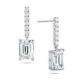 Angled view of the J'ENCHANTE JOY emerald bar stud earrings in 18K white gold. The image highlights the secure stud post and the signature J-shaped side profile, allowing maximum side light entry to enhance the architectural, step-cut clarity of the emerald diamond drop, perfectly paired with a slim pavé-set vertical bar.