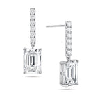 Angled view of the J'ENCHANTE JOY emerald bar stud earrings in 18K white gold. The image highlights the secure stud post and the signature J-shaped side profile, allowing maximum side light entry to enhance the architectural, step-cut clarity of the emerald diamond drop, perfectly paired with a slim pavé-set vertical bar.