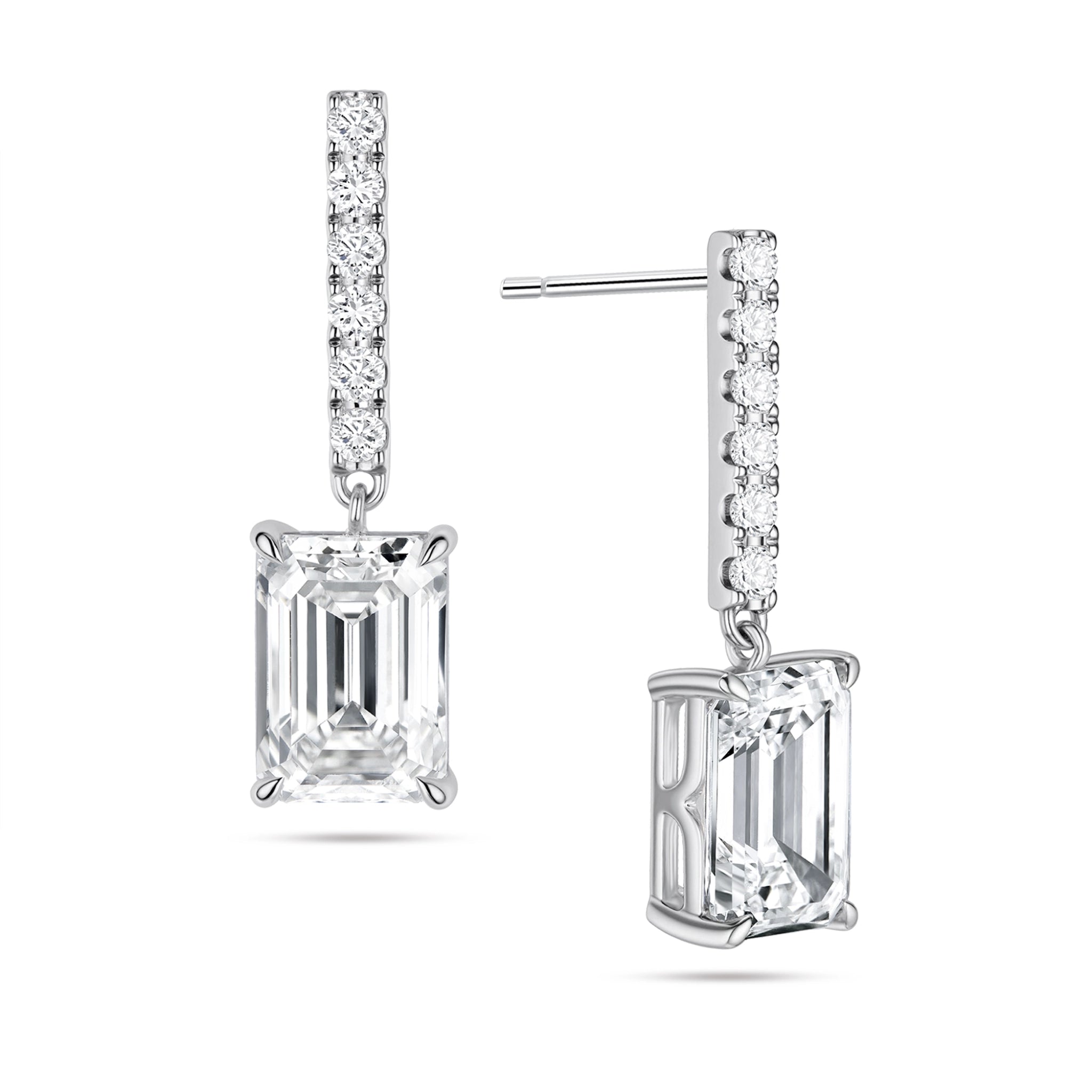 Angled view of the J'ENCHANTE JOY emerald bar stud earrings in 18K white gold. The image highlights the secure stud post and the signature J-shaped side profile, allowing maximum side light entry to enhance the architectural, step-cut clarity of the emerald diamond drop, perfectly paired with a slim pavé-set vertical bar.