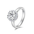 Angled view of the J'ENCHANTE JOY halo solitaire diamond ring in 18K white gold, showcasing a classic four-prong center stone framed by a delicate halo of 20 round diamonds atop a smooth, refined band.