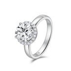 Angled view of the J'ENCHANTE JOY halo solitaire diamond ring in 18K white gold, showcasing a classic four-prong center stone framed by a delicate halo of 20 round diamonds atop a smooth, refined band.