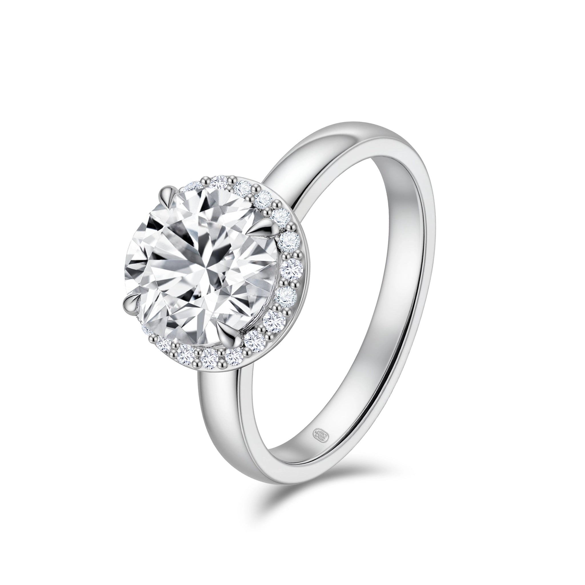 Angled view of the J'ENCHANTE JOY halo solitaire diamond ring in 18K white gold, showcasing a classic four-prong center stone framed by a delicate halo of 20 round diamonds atop a smooth, refined band.