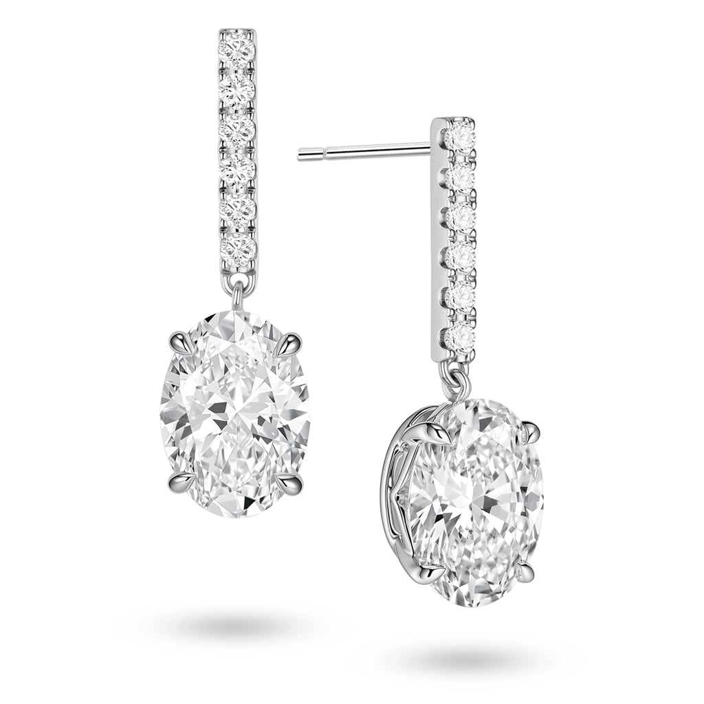 Angled view of the J'ENCHANTE JOY oval bar stud earrings, highlighting the secure stud post and the signature J-shaped side profile of the sculpted setting. This design maximizes side light entry to enhance the clarity and dimension of the oval diamond drop.