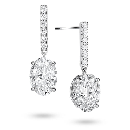 Angled view of the J'ENCHANTE JOY oval bar stud earrings, highlighting the secure stud post and the signature J-shaped side profile of the sculpted setting. This design maximizes side light entry to enhance the clarity and dimension of the oval diamond drop.