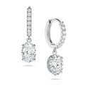 Angled view of the J'ENCHANTE JOY oval drop earrings in 18K white gold. The image showcases a pair of slim pavé hoops and graceful oval-cut drops, highlighting the signature J-shaped side profile designed to maximize side light entry for enhanced diamond clarity and dimension.