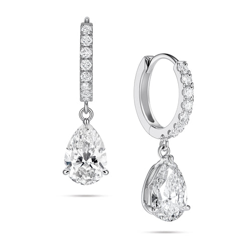 Angled view of the J'ENCHANTE JOY pear drop earrings in 18K white gold. The image showcases a pair of slim pavé hoops and graceful pear-shaped drops, with one earring highlighting the signature J-shaped side profile designed to securely support the diamond while maximizing side light entry for enhanced dimension.