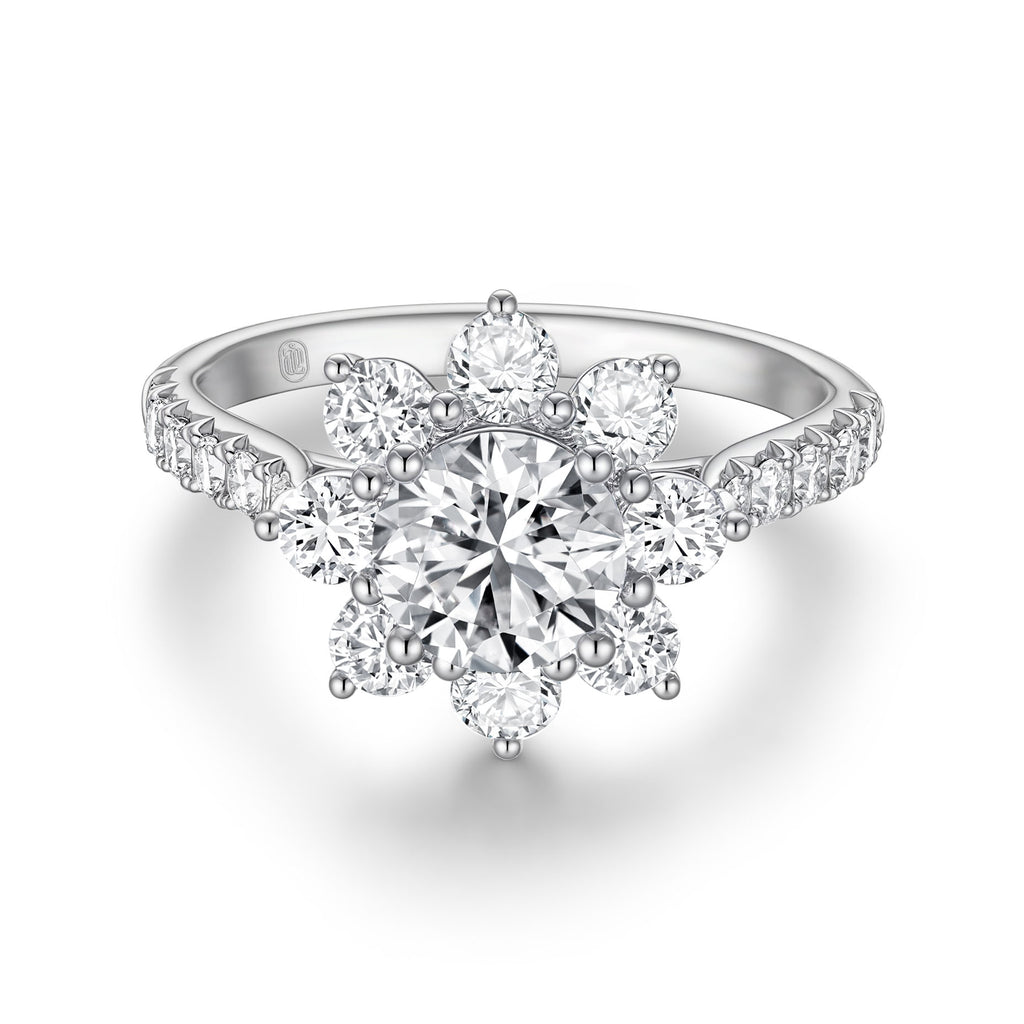 Front view of the J'ENCHANTE LIFE Full Bloom diamond ring in white gold. A commanding 1-carat round center diamond is encircled by a radiant sunflower-inspired halo. Paired with a delicately pavé-set band featuring 22 round diamonds (approx. 1.0 carats), the design creates a stunning, luminous floral silhouette.