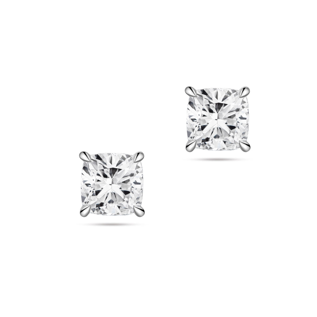 Front view of the J'ENCHANTE ONE cushion-cut diamond stud earrings in white gold. The minimalist design features a brilliant cushion-cut diamond on each ear. The soft, rounded corners of the cushion cut offer a pure vision of form, light, and balance for timeless everyday elegance.