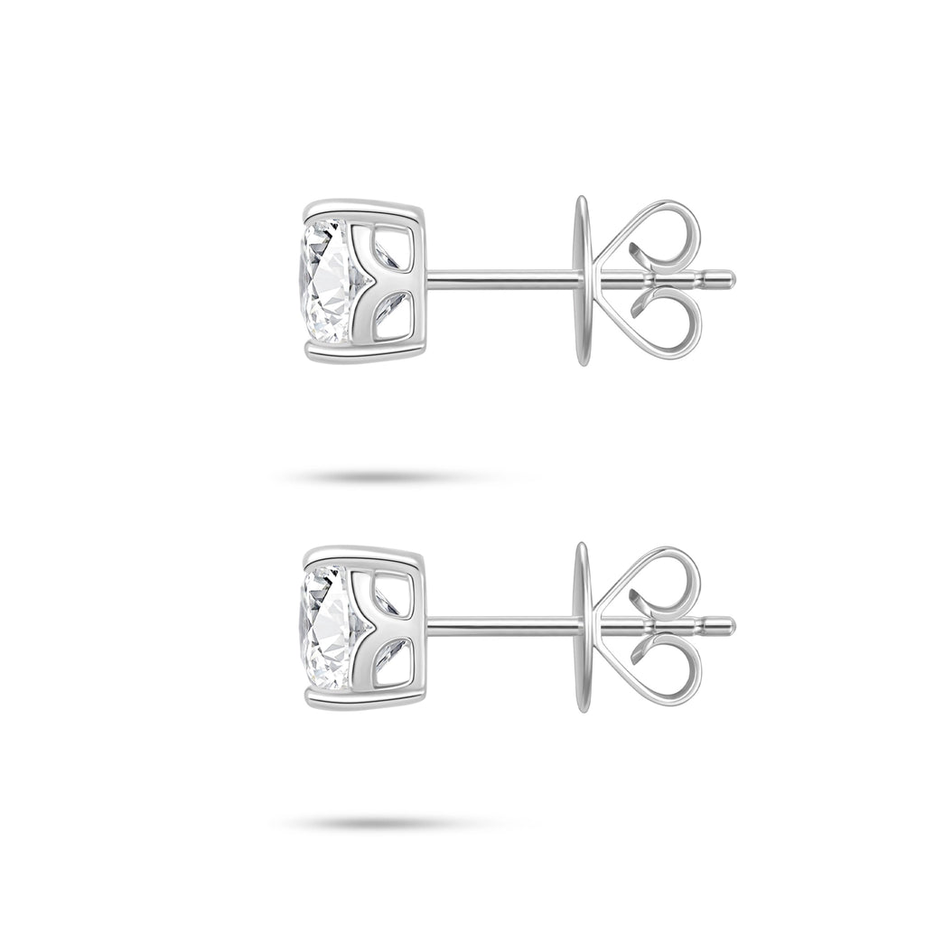 Side profile view of the J'ENCHANTE ONE cushion-cut diamond stud earrings, highlighting the signature J-setting and secure earring backs. The graceful architectural curve cradles and lifts the stone from the side, drawing in light to enhance the depth and brilliance of the diamond.