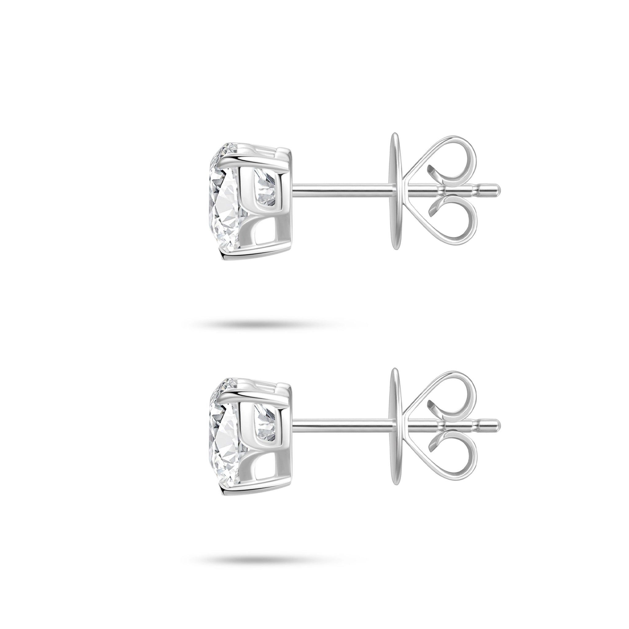 Side profile view of the J'ENCHANTE ONE heart diamond stud earrings, highlighting the signature J-setting and secure earring backs. The refined architectural curve cradles the heart-cut stone from the side, allowing light to enter freely to enhance its depth and radiant brilliance.