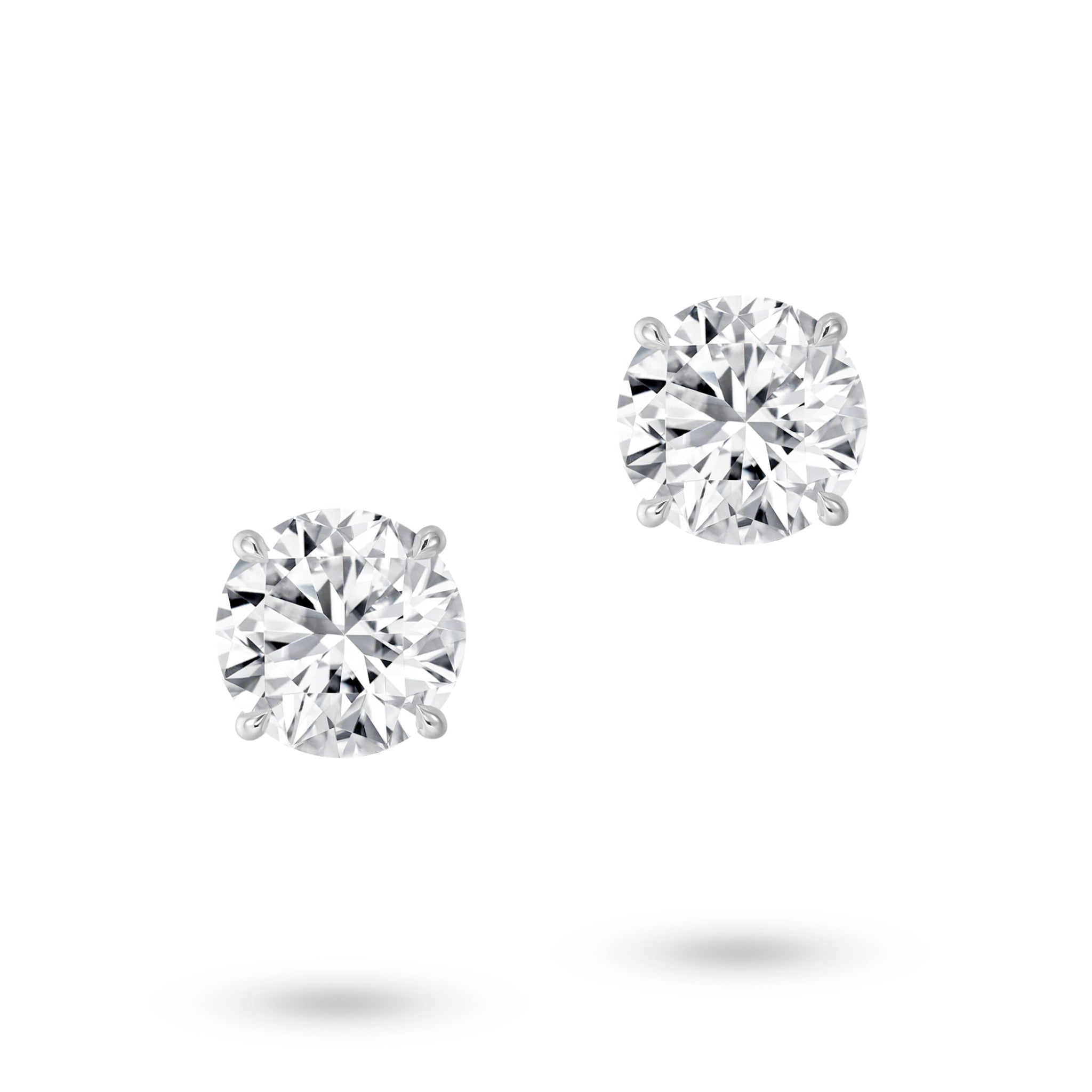 Front view of the J'ENCHANTE ONE round cut diamond stud earrings, featuring a magnificent 2-carat brilliant round diamond on each ear. Free from embellishment, the minimalist white gold design expresses the purest relationship between form and light.