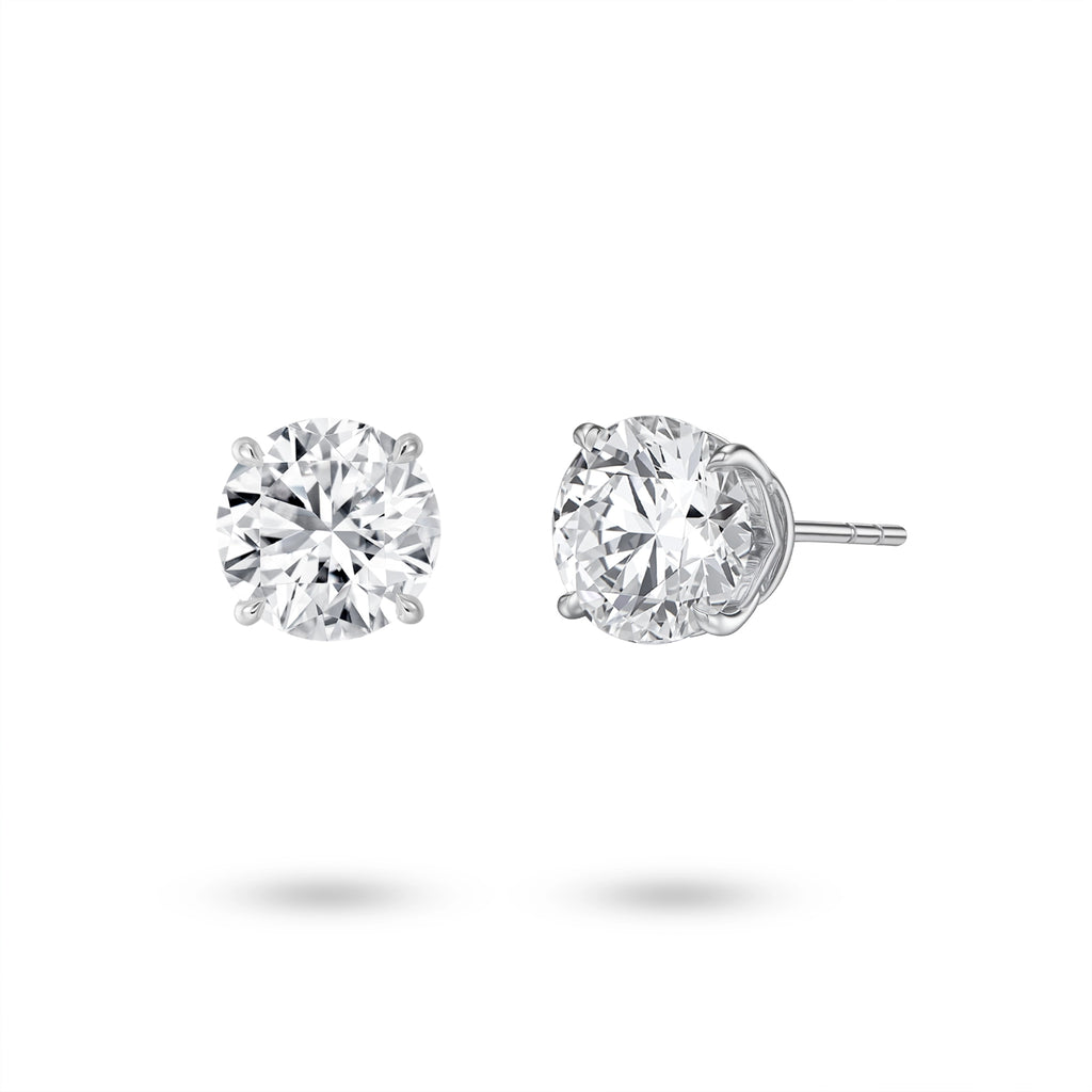 Angled view of the J'ENCHANTE ONE 2-carat round diamond stud earrings, highlighting the signature J-setting. The elegant, architectural curve lifts the stone, allowing light to enter from every angle for maximized brilliance and proportion.