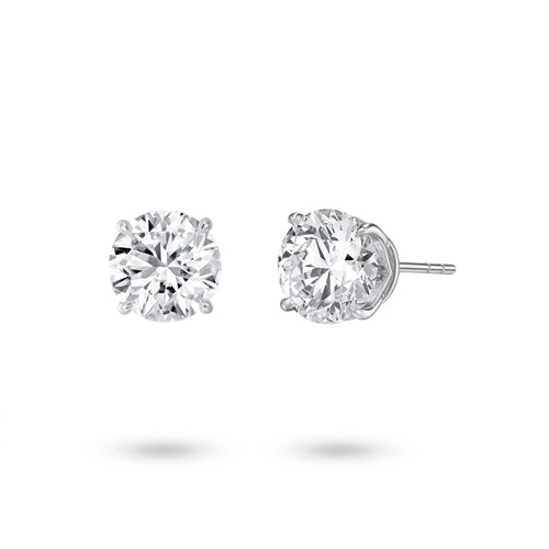 Angled view of the J'ENCHANTE ONE 2-carat round diamond stud earrings, highlighting the signature J-setting. The elegant, architectural curve lifts the stone, allowing light to enter from every angle for maximized brilliance and proportion.