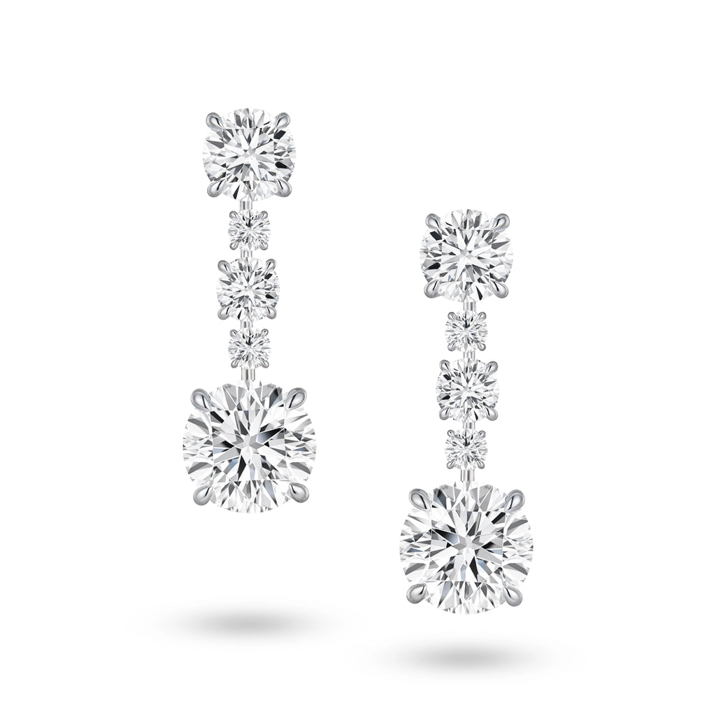 Front view of the J'ENCHANTE The Radiant Line diamond earrings in 18K white gold. Defined by a pure vertical composition, a precise sequence of graduating round brilliant diamonds unfolds into two commanding 3.0-carat bottom anchor stones (10 diamonds totaling approx. 9.08 carats). This flawless alignment creates a continuous, luminous flow of radiance for an elegant and effortless statement.
