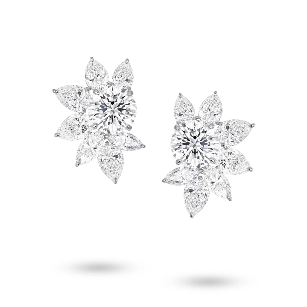 Front view of the J'ENCHANTE The Solaris Bloom high jewelry diamond earrings in 18K white gold. Each earring is anchored by a commanding 3.0-carat round brilliant center stone, from which pear and marquise-cut diamonds unfold in a luminous, petal-like formation (16 diamonds totaling approx. 14.07 carats). This perfectly symmetrical, sculptural bloom embodies the peak of brilliance and striking power.