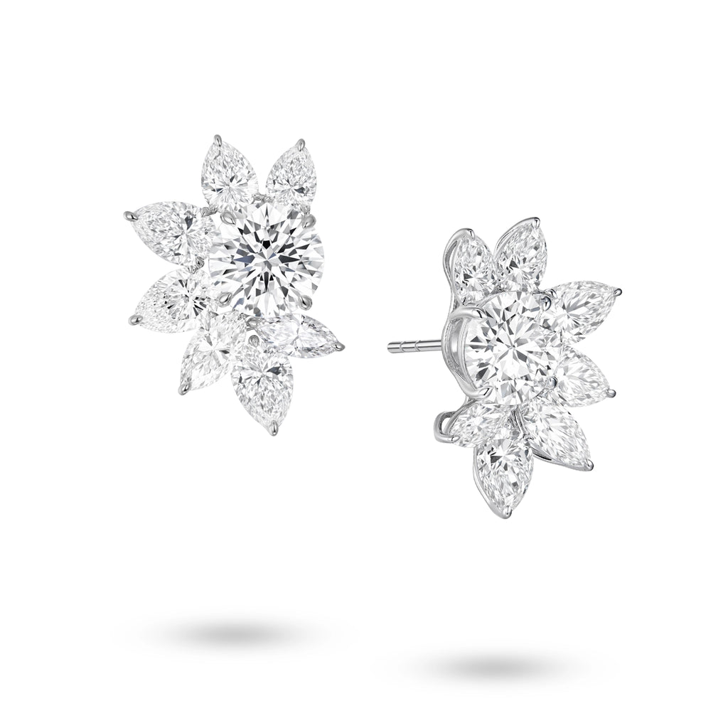 Angled view of the J'ENCHANTE The Solaris Bloom statement diamond earrings. The image highlights the 18K white gold setting and secure earring posts. This perspective reveals the striking three-dimensional depth and the intricate interplay of round, pear, and marquise-cut diamonds. This expertly arranged mixed-cut cluster enhances directional light, ensuring outward brilliance and clarity from every possible angle.
